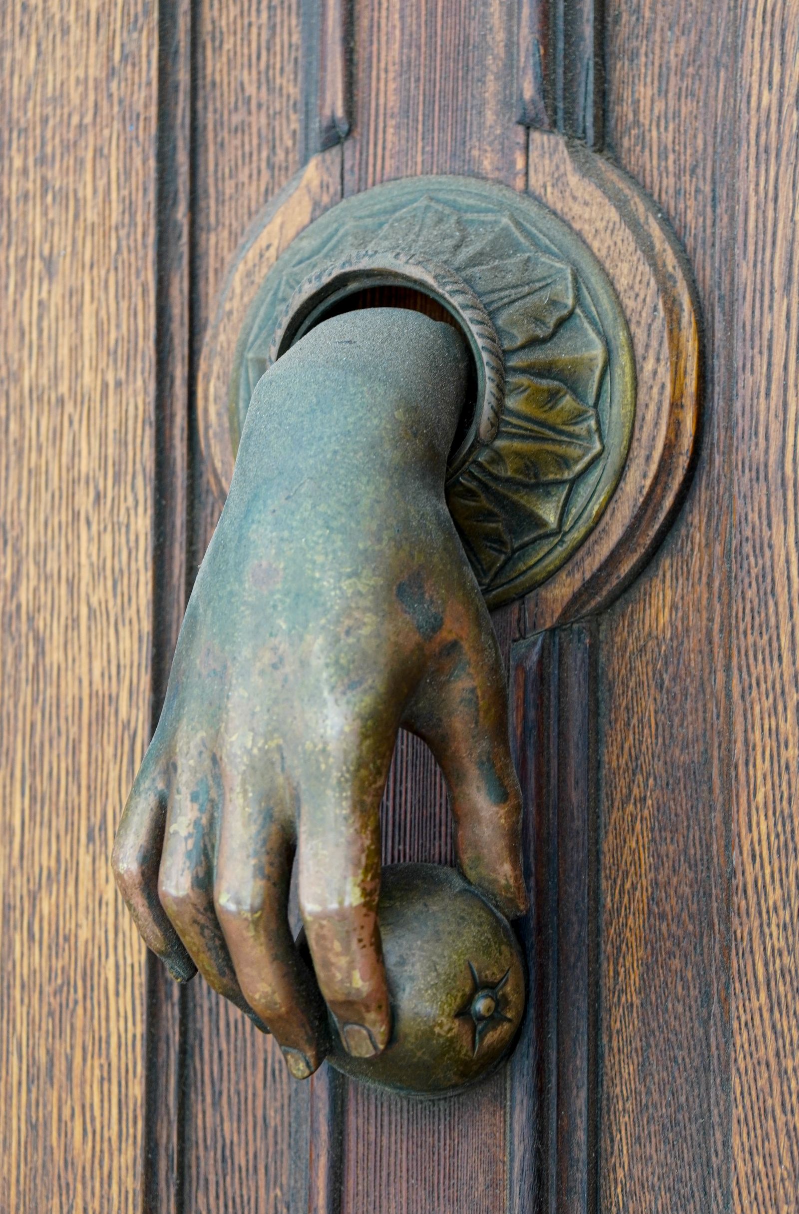 A weathered wooden door with an ornate bronze knocker, Spain